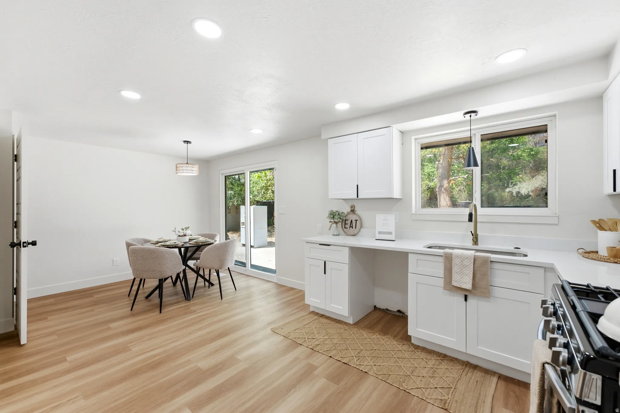 Open-concept kitchen and dining area featuring light wood-finish flooring, recessed lighting, and a sliding glass door leading to the exterior