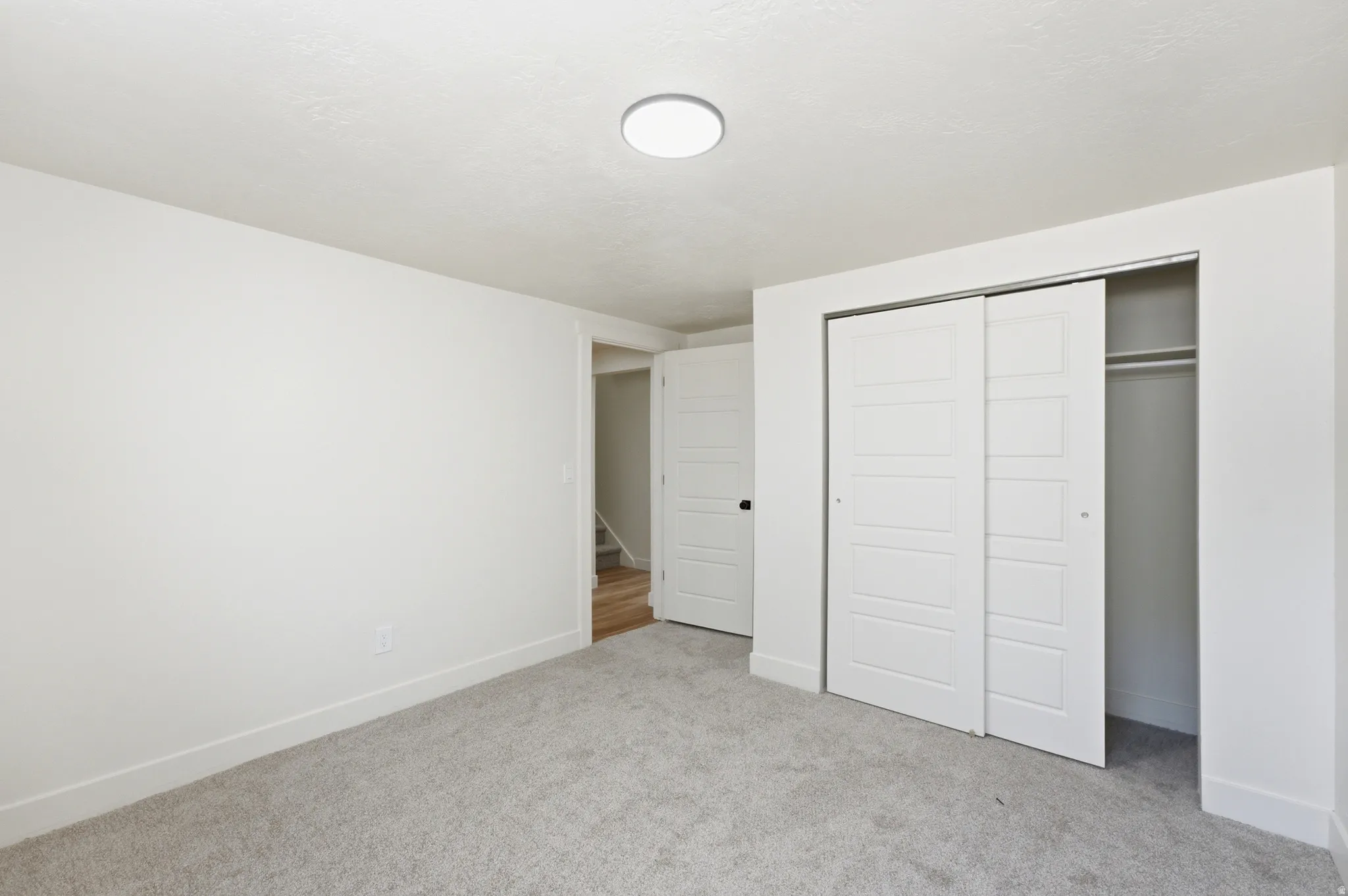 Neutral-toned carpet flooring with white baseboards and walls