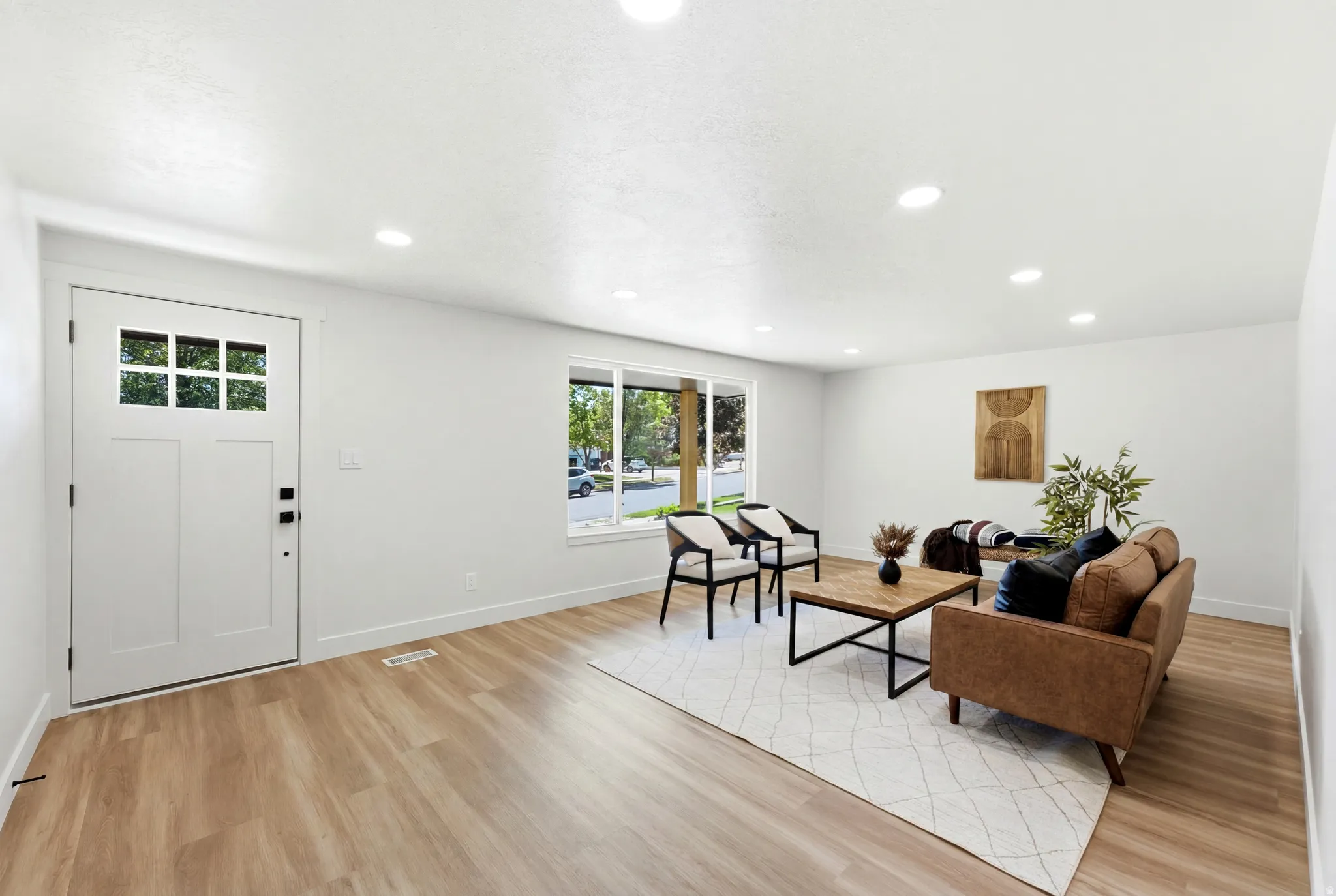 Bright living area featuring wood-finish flooring, recessed lighting, and a multi-pane front entry door