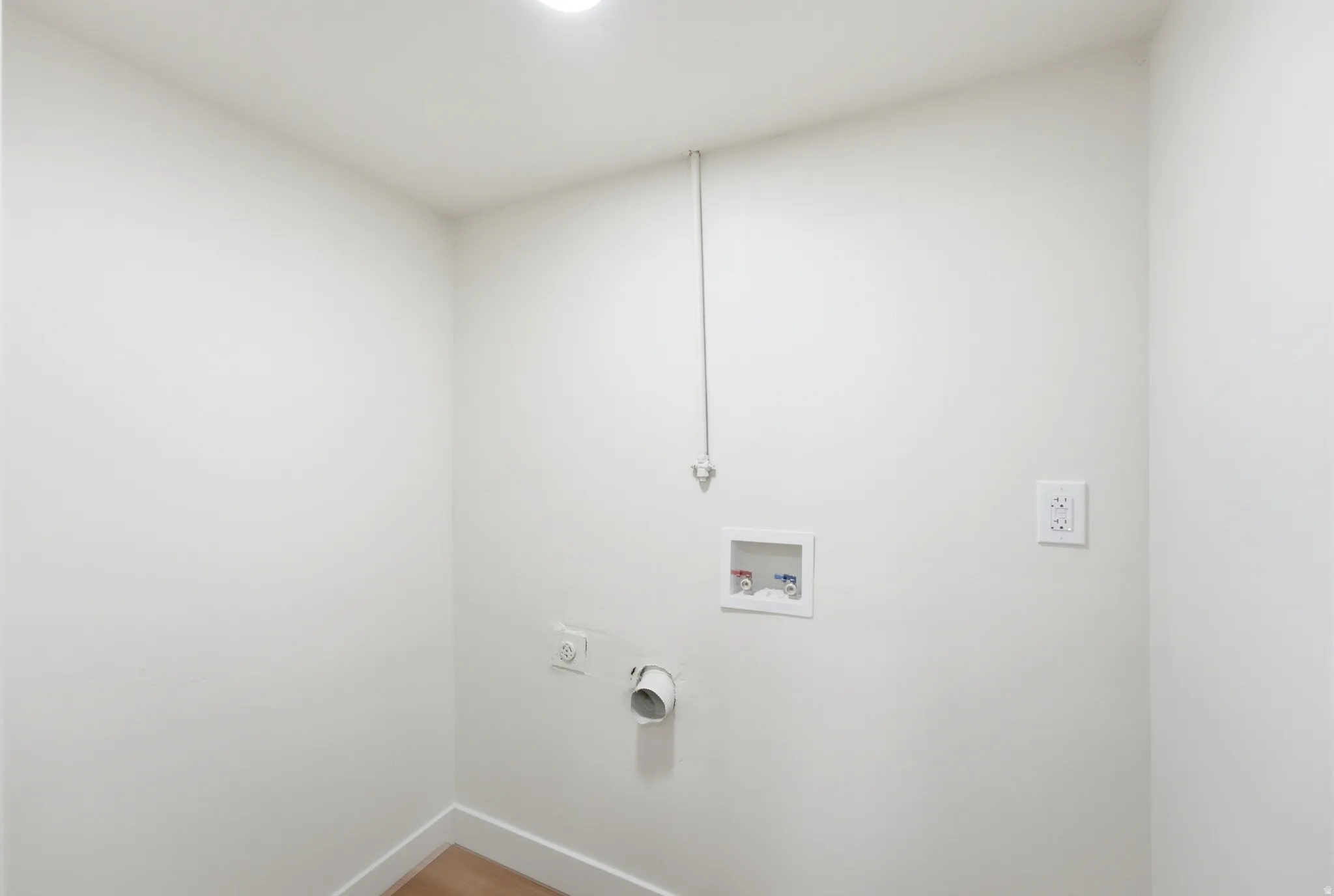 Dedicated laundry area with white walls and wood-finish flooring