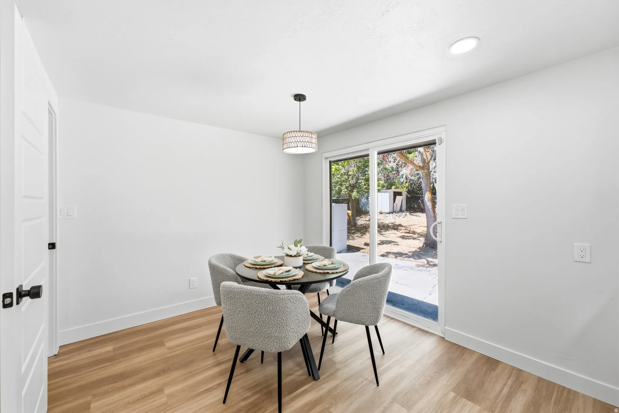Dining area featuring wood-finish flooring, a contemporary pendant light fixture, recessed ceiling lighting, and a sliding glass door providing access to the exterior