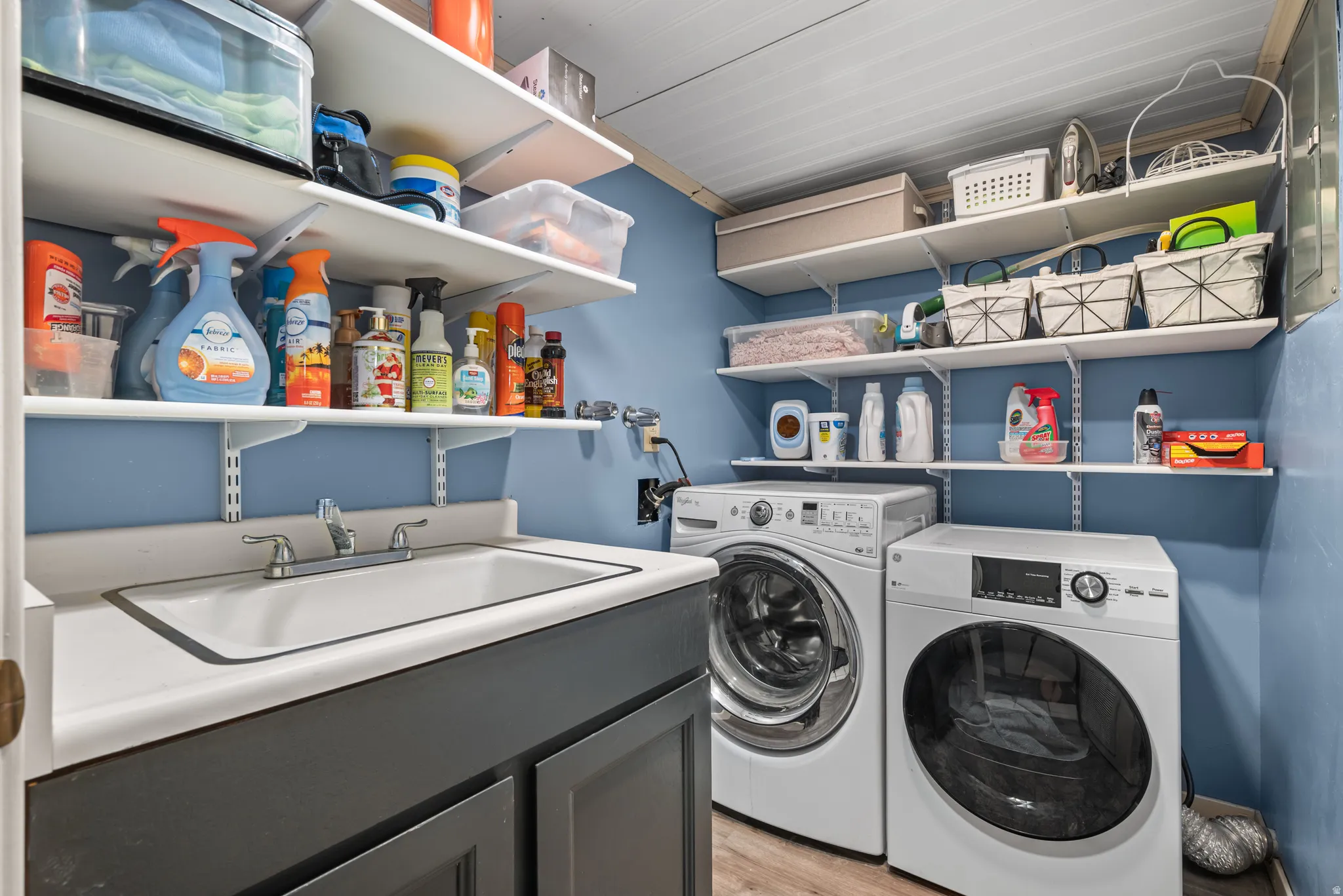 Dedicated laundry room featuring a utility sink with a cabinet base, a side-by-side washer and dryer, and extensive wall-mounted shelving