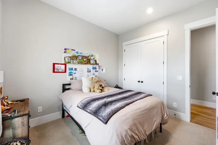 Carpeted room featuring a double-door closet with black hardware, white trim, and light gray walls