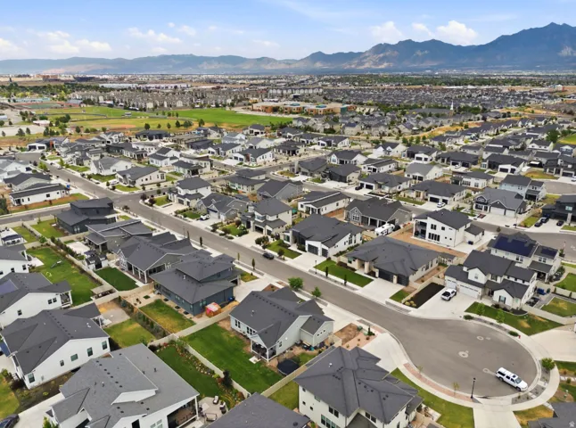 Aerial overview of a residential community featuring various single-family homes, paved roads, and green spaces
