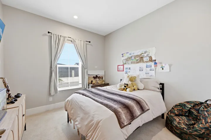 Neutral-toned room featuring a large window with blinds, recessed lighting, and light-colored carpeting