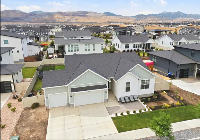 Contemporary ranch-style home featuring a two-car garage, light-toned siding with horizontal and vertical accents, and a dark shingle roof