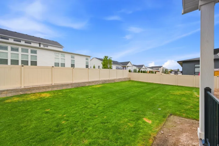 Expansive green lawn surrounded by a light-toned privacy fence