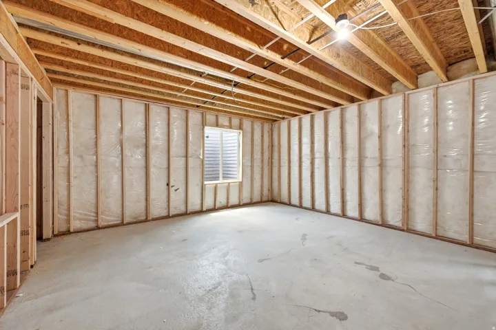 Unfinished basement with exposed ceiling joists and concrete flooring