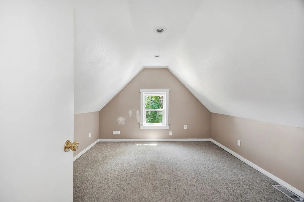 Bedroom featuring sloped ceilings, recessed lighting, and a single window with white trim