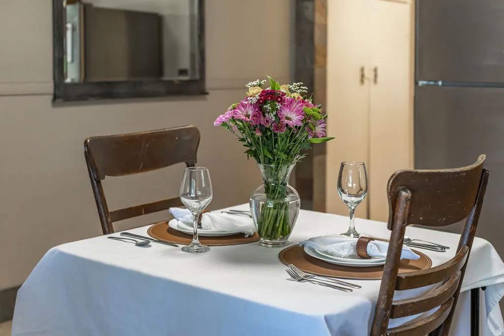 Dining area with a white tablecloth, two place settings, and a floral centerpiece