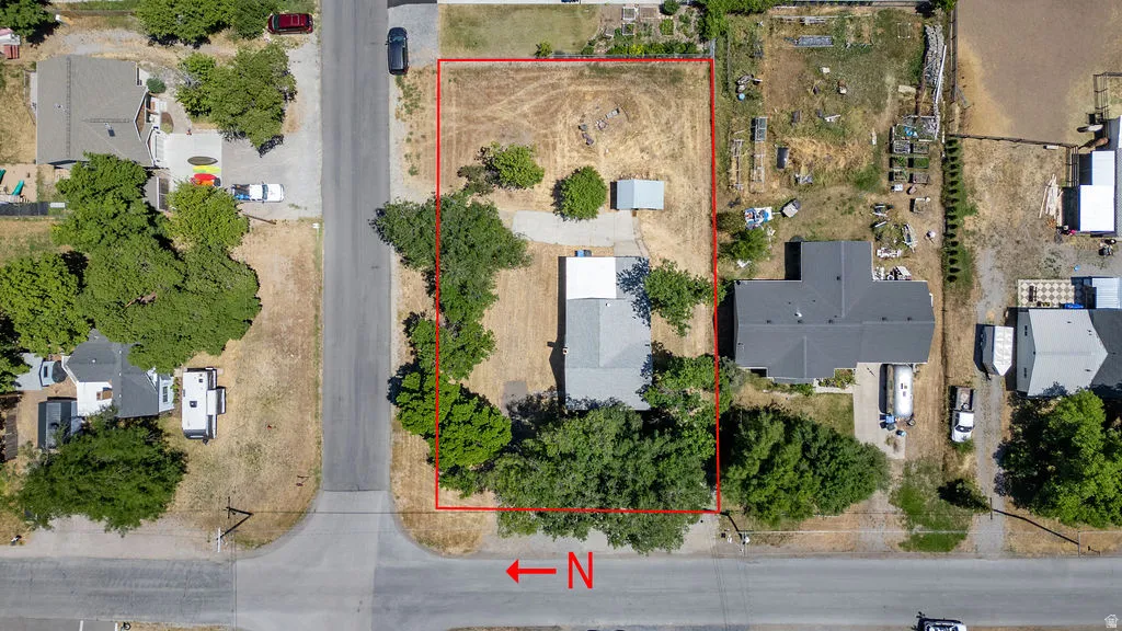 Aerial perspective showcasing a corner lot property with established trees and a substantial land area