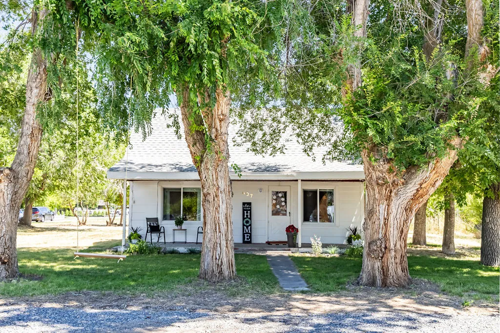 White residence with a gabled roof and mature shade trees