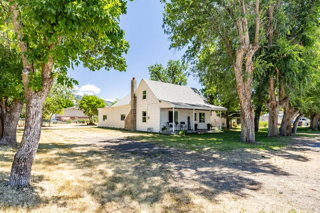 White exterior residence featuring a covered front porch and ample parking on all sides