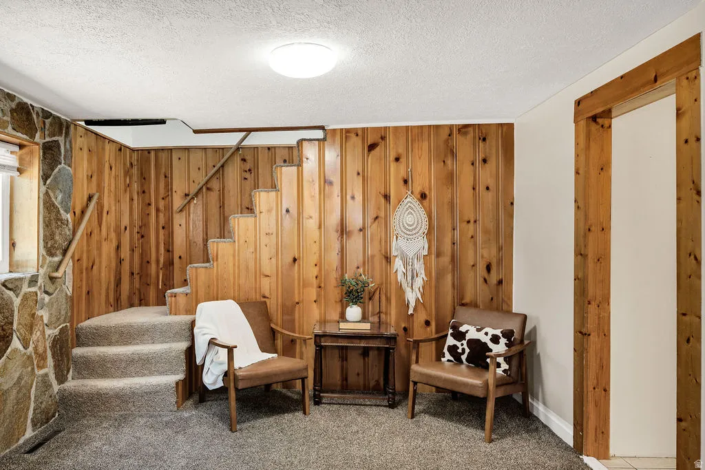 Carpeted staircase with wood paneling and stone wall accents