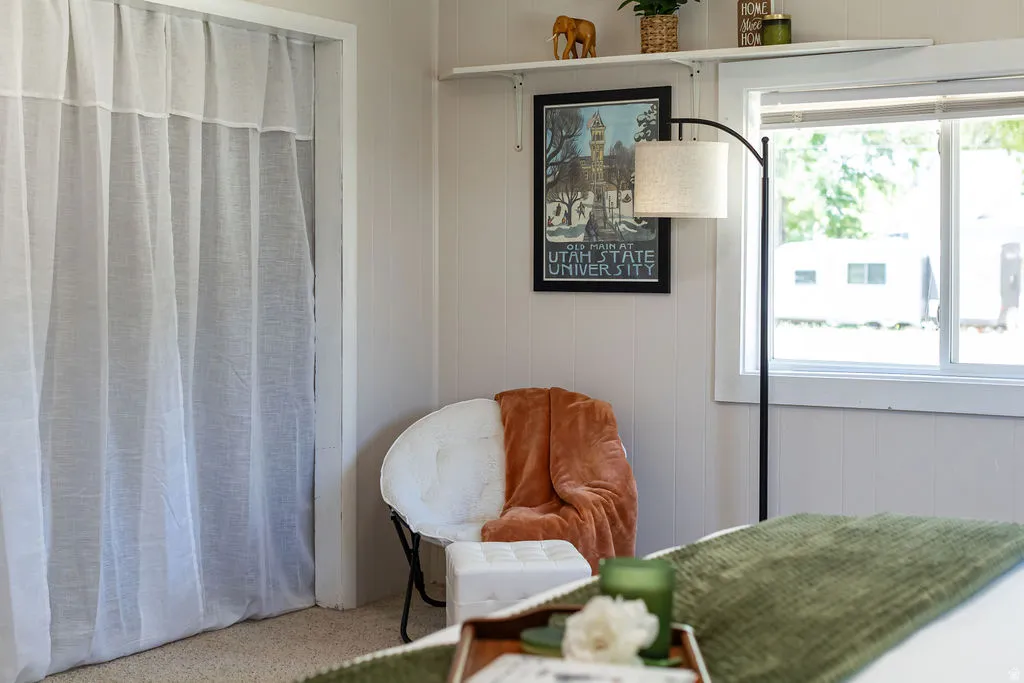 Light-filled interior featuring white paneling, a large window, and light-toned carpet flooring
