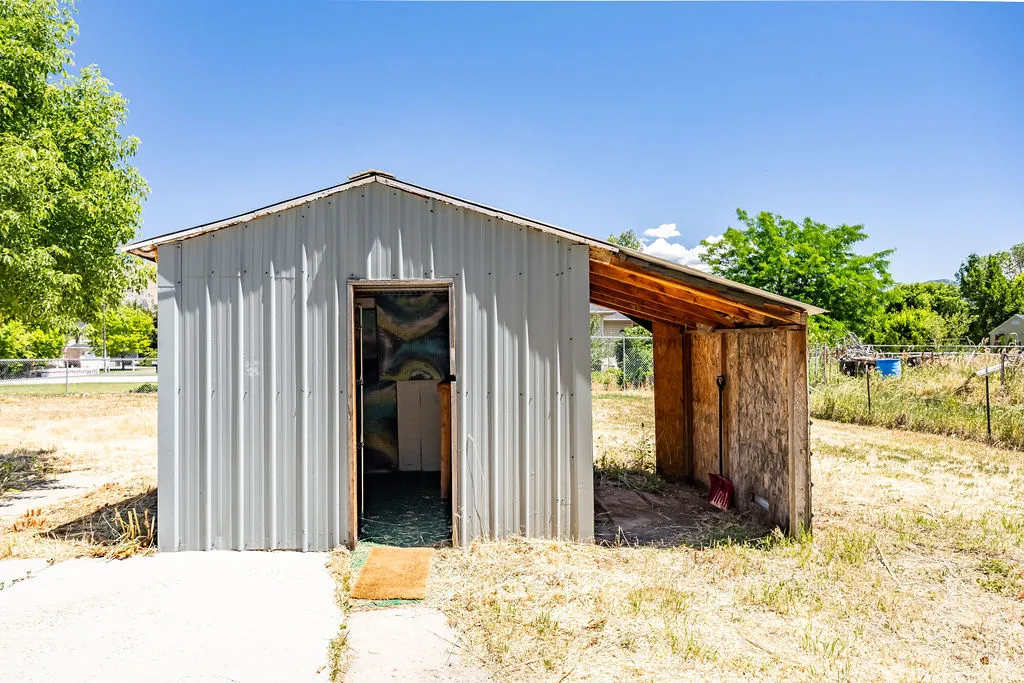 Metal utility shed with an attached covered lean-to, featuring a concrete pad entrance