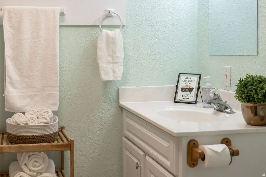 Bathroom vanity featuring a single basin sink, white countertop, and white cabinetry