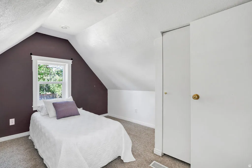 Attic room featuring sloped ceilings, recessed lighting, a single window, and neutral carpet flooring