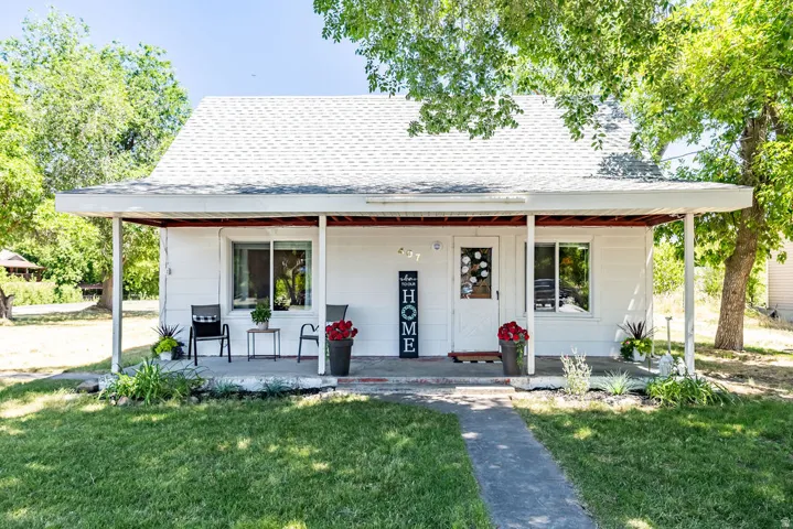 Cozy country home featuring a covered front porch, a gabled roof with shingles, and a concrete pathway