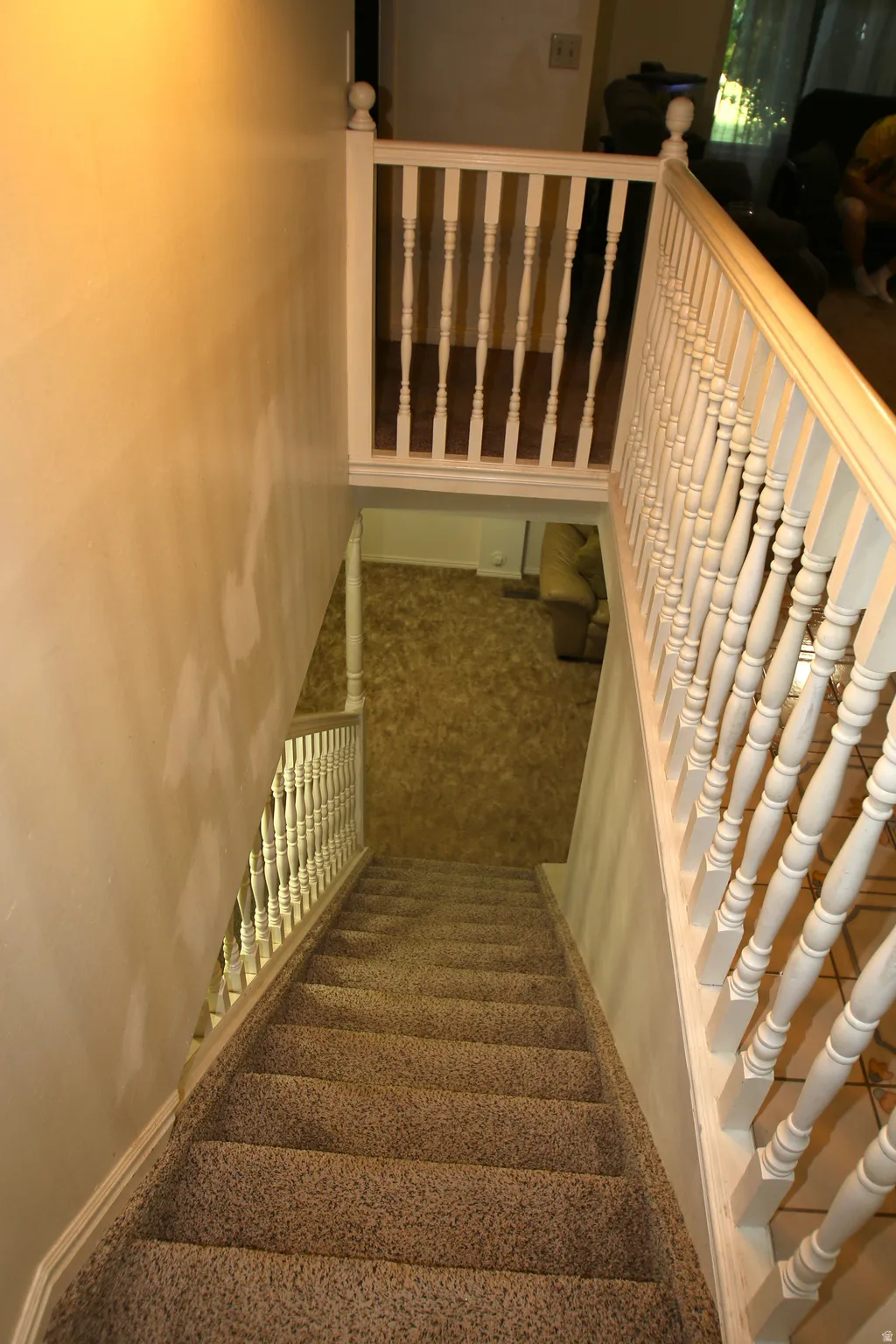 Carpeted staircase with white painted wood balusters and newel posts