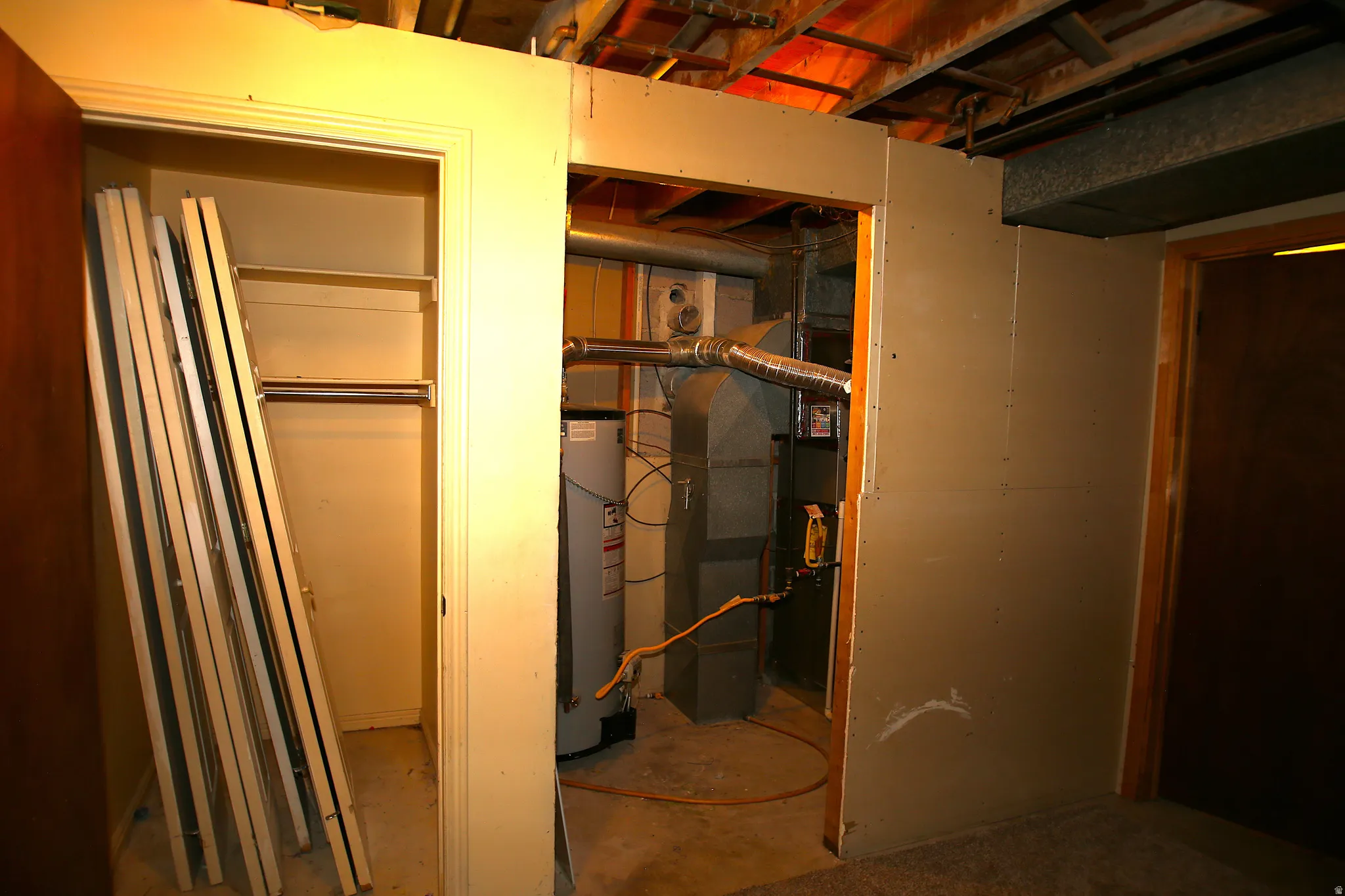Utility area featuring a water heater, furnace, and exposed ceiling joists