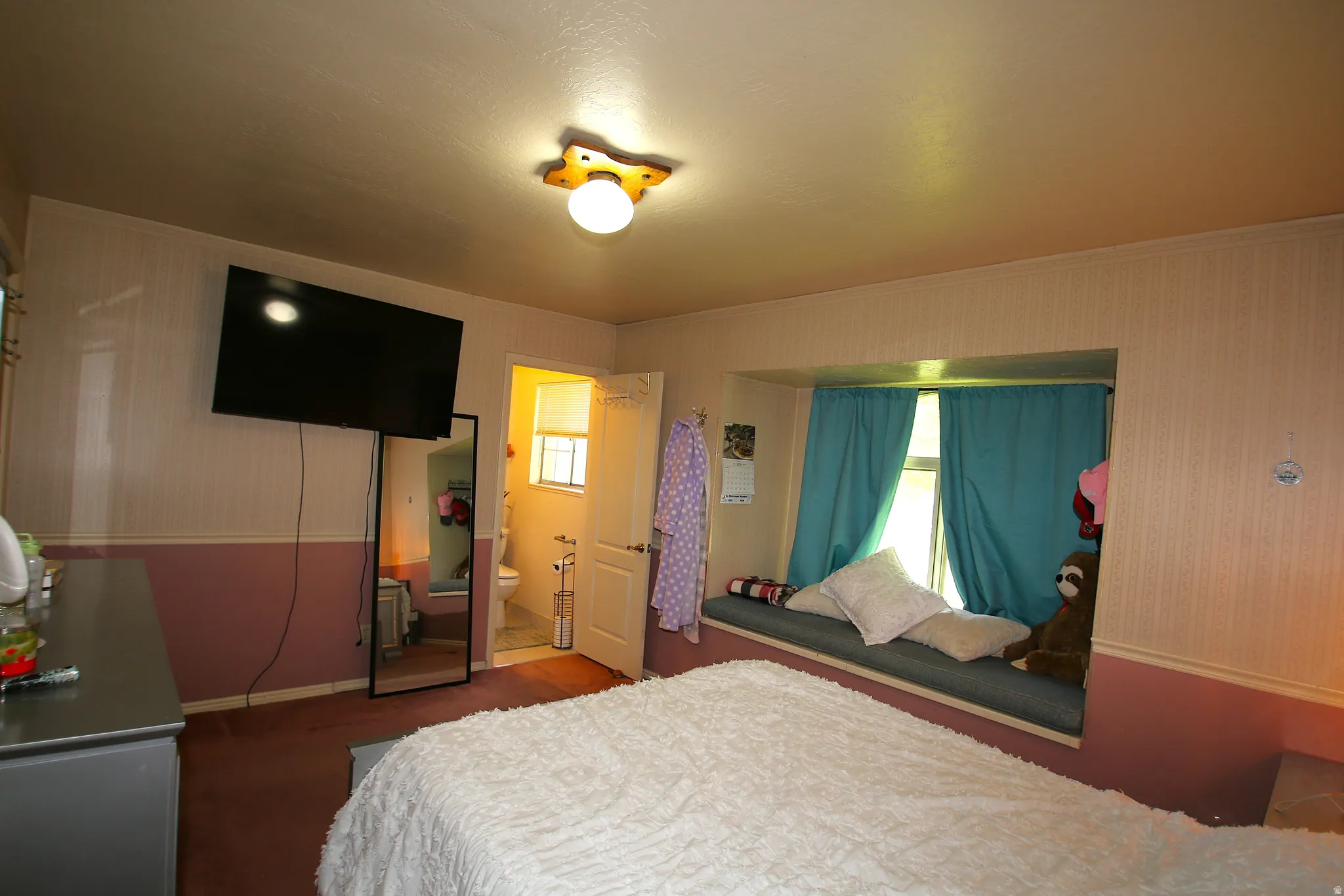 Bedroom featuring a built-in window seat, recessed window, and wall-mounted television