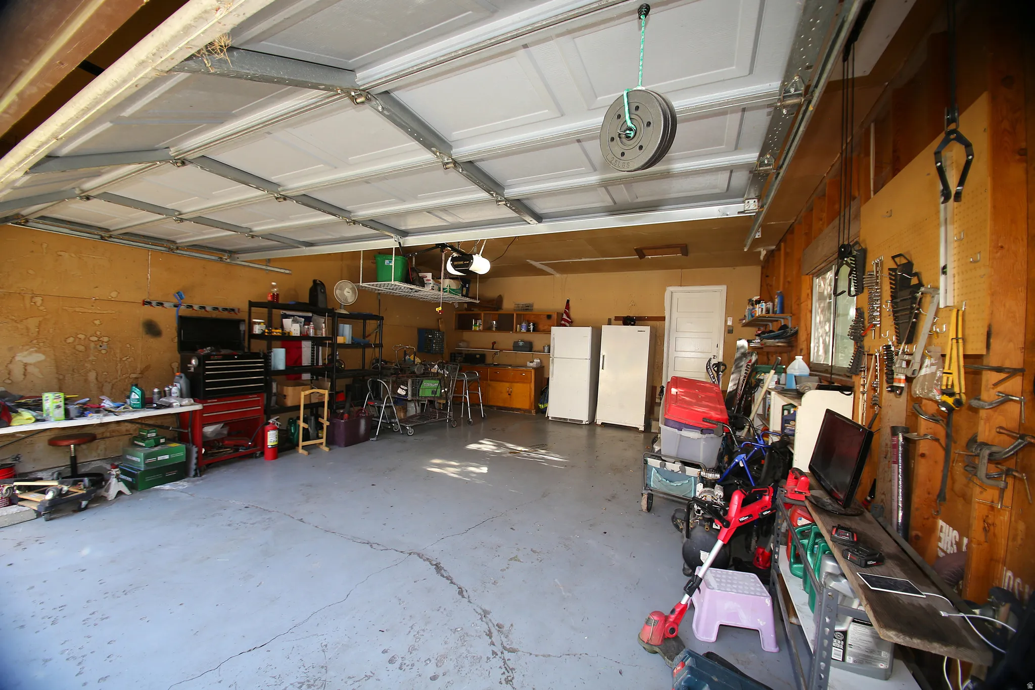 Spacious garage featuring a concrete floor, overhead garage door with track system, and an interior access door