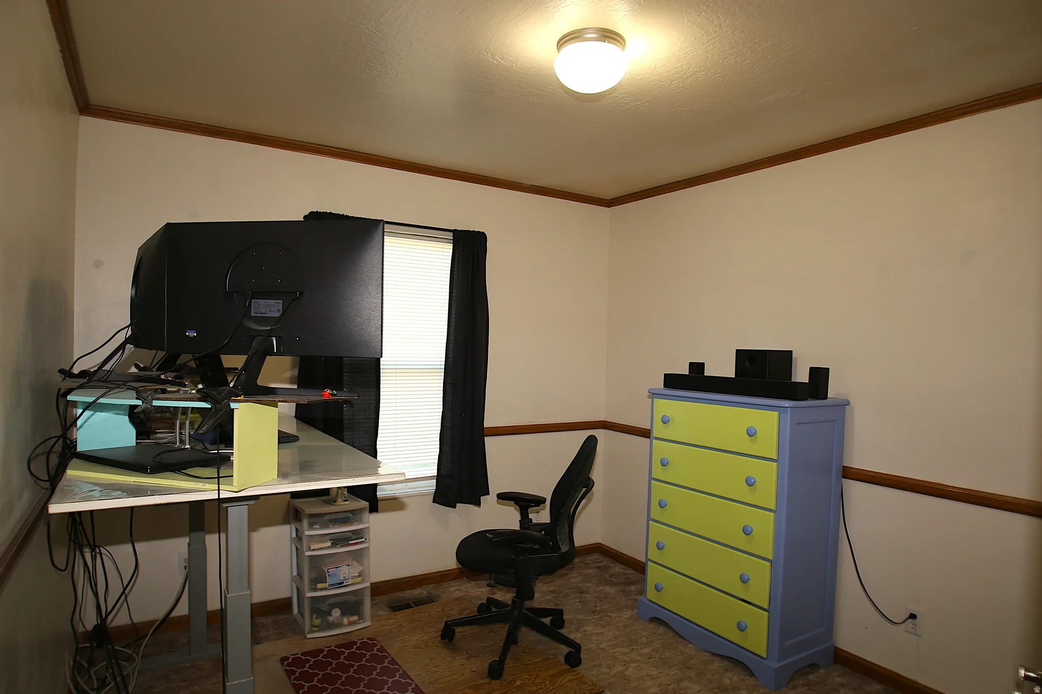 Interior room featuring a window with blinds, wall-mounted ceiling light fixture, and wood trim molding