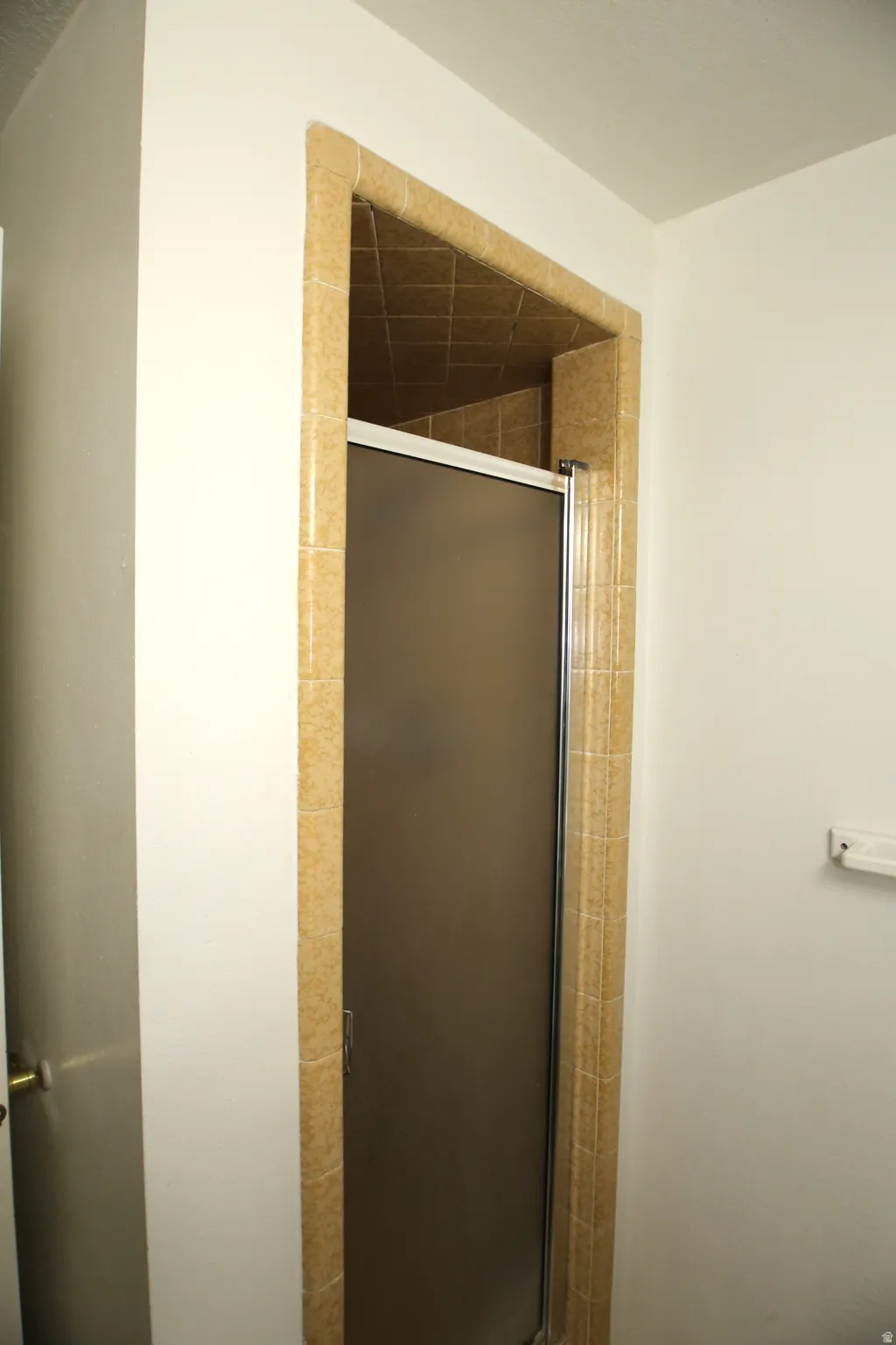 Shower enclosure featuring frosted glass sliding doors and full-height tile surround