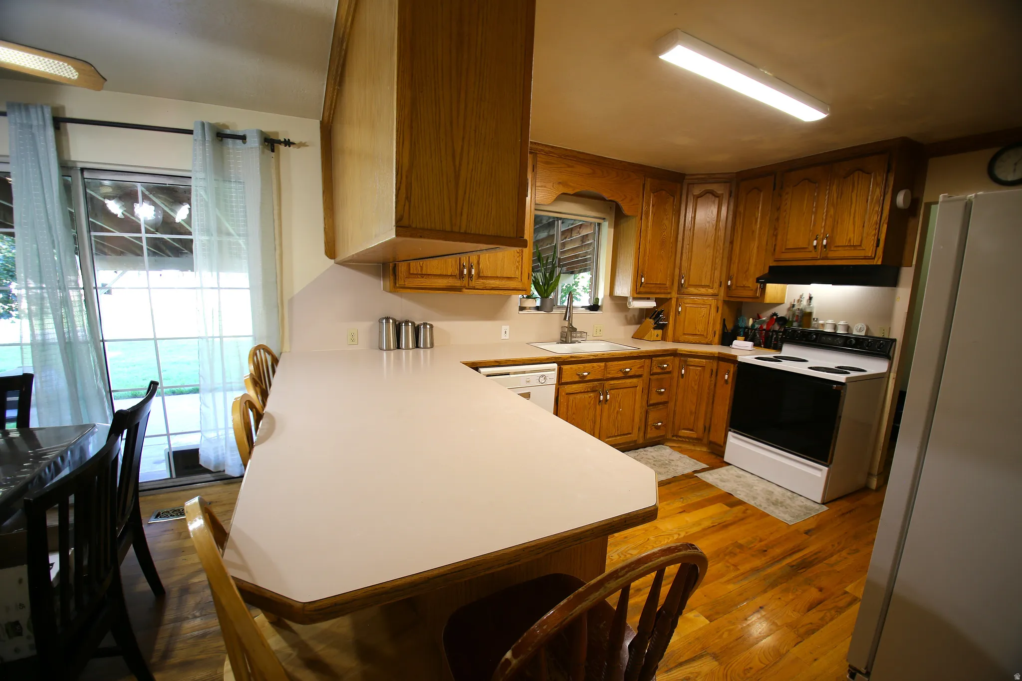 Kitchen featuring wood-finish flooring, light wood cabinetry, a white countertop, and a white oven