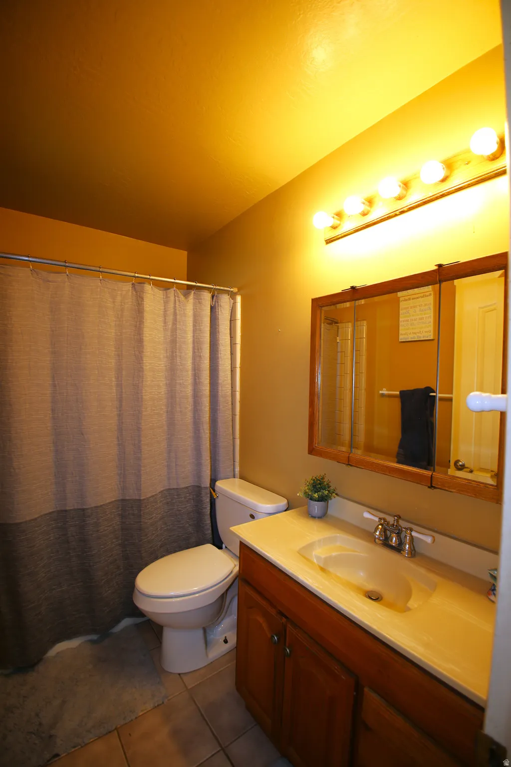 Bathroom with a wood-finish vanity, integrated sink, and wall-mounted light bar