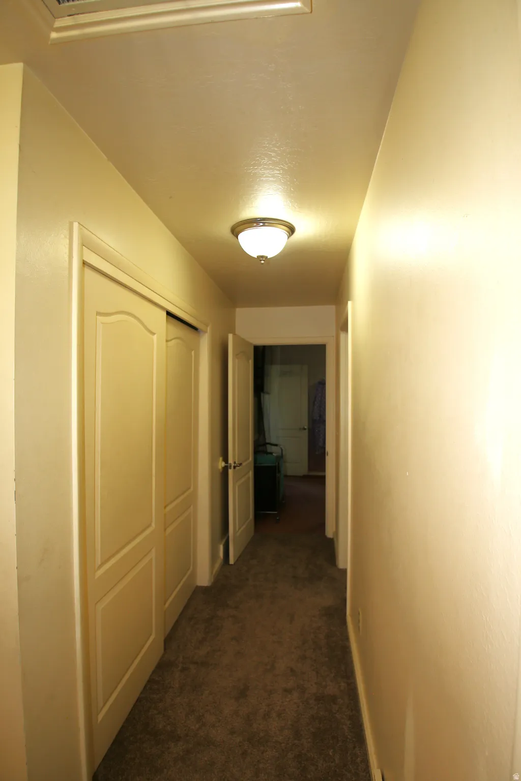 Hallway featuring a semi-flush mount ceiling light fixture, neutral-toned walls, and brown carpet flooring