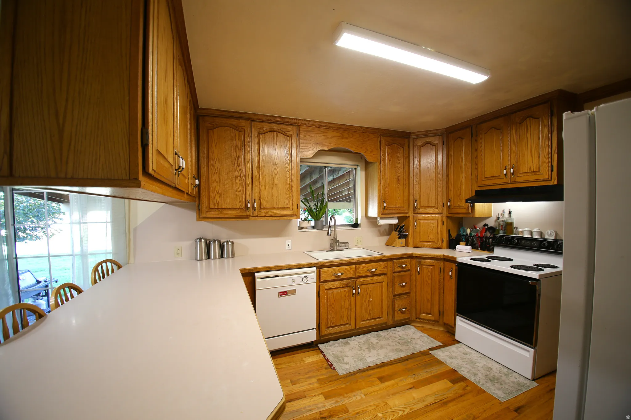 Kitchen featuring extensive wood cabinetry, wood-finish flooring, and white countertops