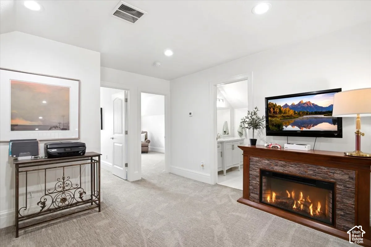 Carpeted room featuring a built-in electric fireplace with stone-look surround and wood-finish mantel, white walls, and recessed lighting