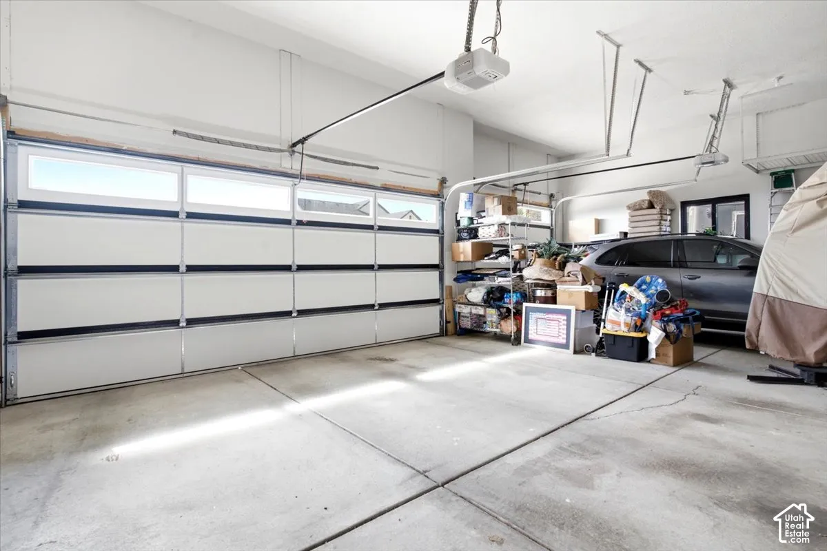 Two-car garage featuring a sectional garage door with upper window inserts, concrete flooring, and an automatic garage door opener