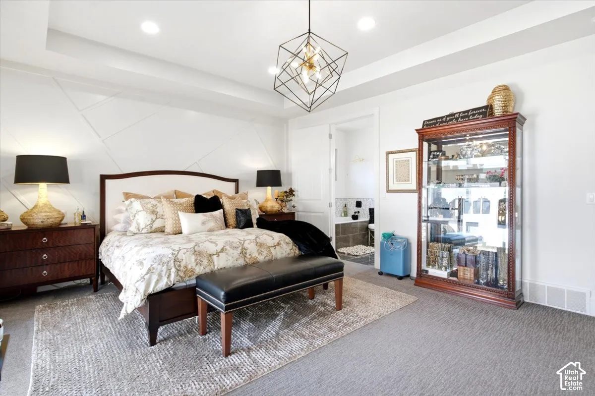 Spacious bedroom featuring textured accent wall paneling, a recessed tray ceiling, and a modern geometric pendant light fixture