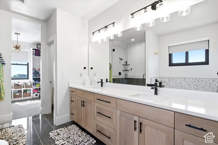 Dual sink vanity with quartz countertops, wood-finish cabinetry, and matte black fixtures