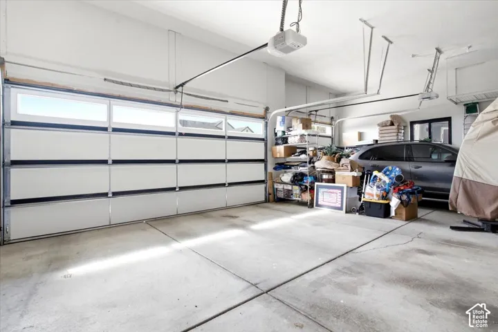 Two-car garage featuring a sectional garage door with upper window inserts, concrete flooring, and an automatic garage door opener