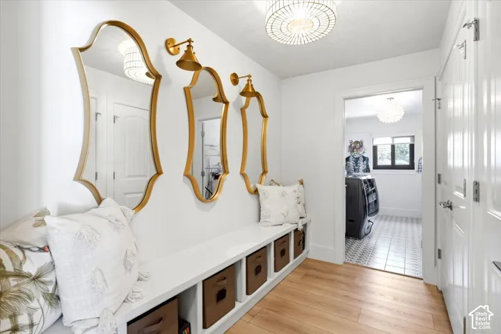 Entryway featuring wood-finish flooring, a built-in bench with integrated cubby storage, and three decorative gold-framed mirrors with coordinating wall sconces