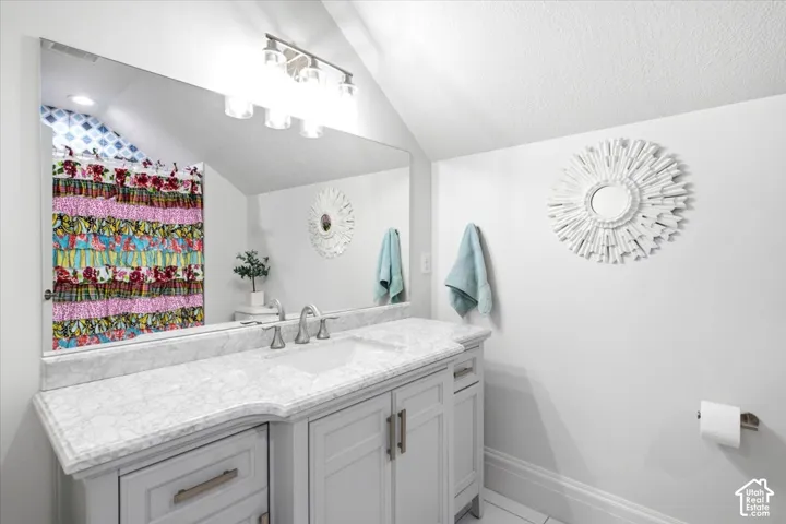 Bathroom featuring a single vanity with a light-toned countertop, an integrated sink, and brushed nickel fixtures
