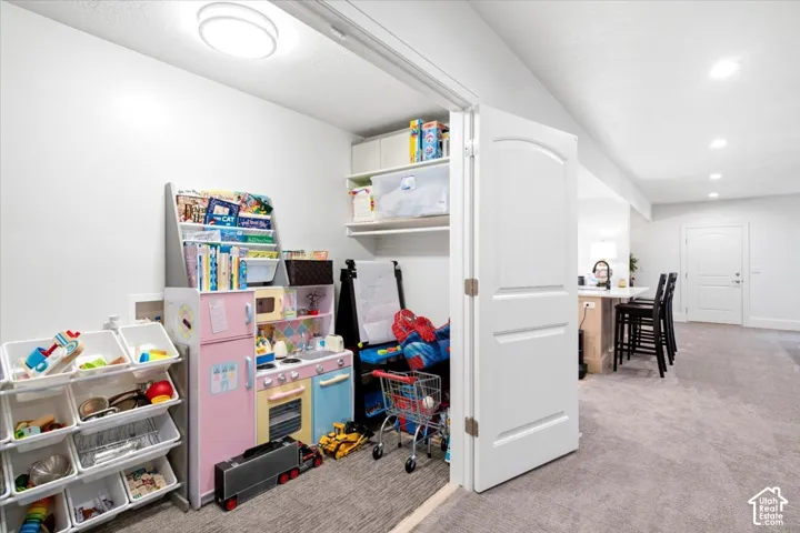 Recessed lighting illuminates the carpeted floor area, featuring a built-in closet with shelves