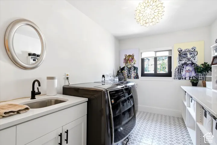 Dedicated laundry room featuring patterned floor tiles, a window, and a decorative ceiling light fixture