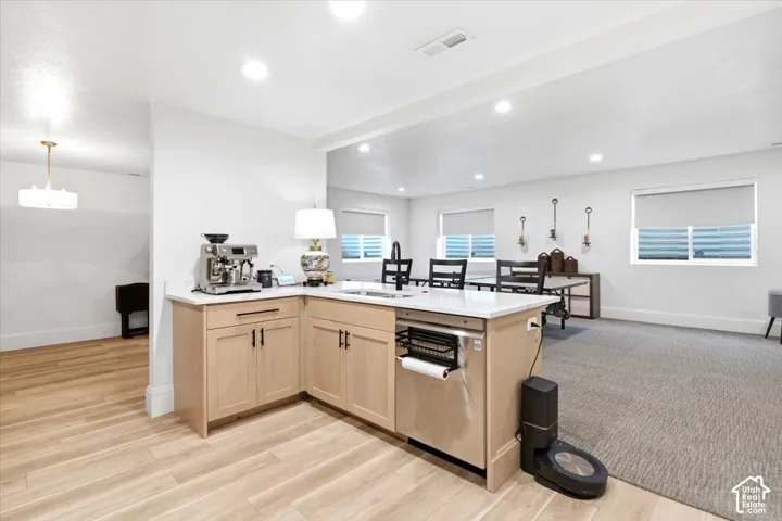L-shaped kitchen island featuring light wood-finish cabinetry and a light-toned countertop