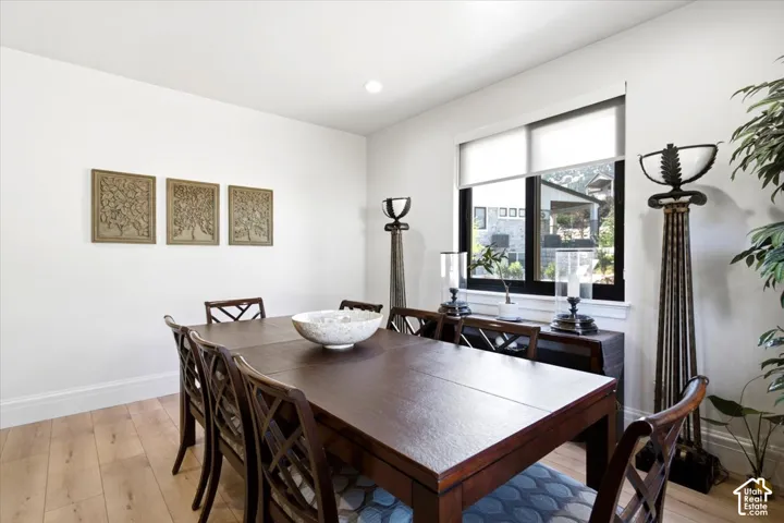 Spacious dining area featuring light wood-finish flooring, white baseboards, and bright white walls