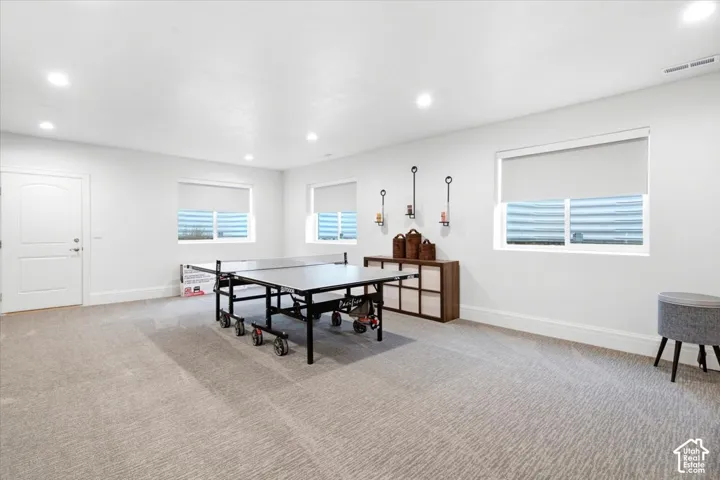 Spacious room featuring neutral carpeting, recessed lighting, and multiple windows with roller shades