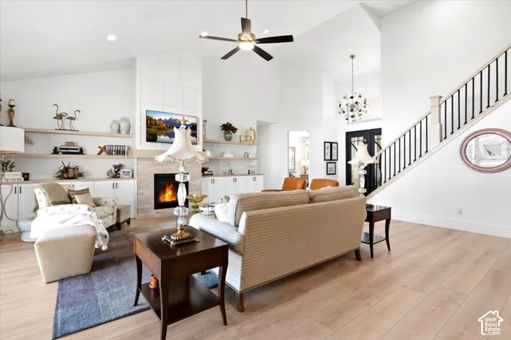 Vaulted living space featuring a fireplace with stone surround, custom built-in cabinetry, and wood-finish flooring
