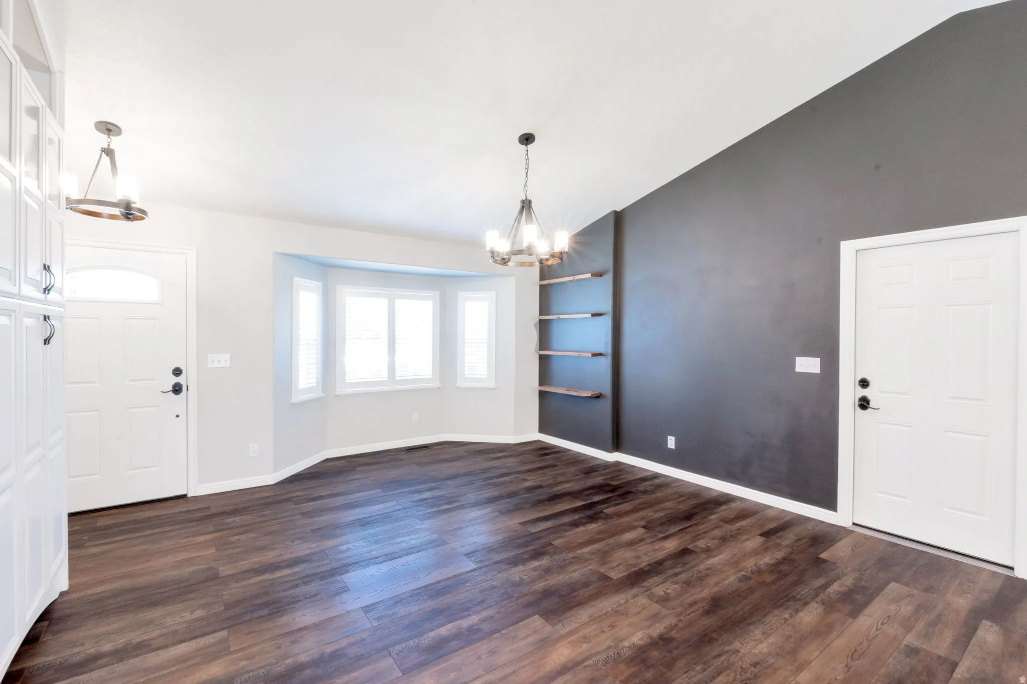 Spacious room featuring wood-finish flooring, a bay window, and a vaulted ceiling