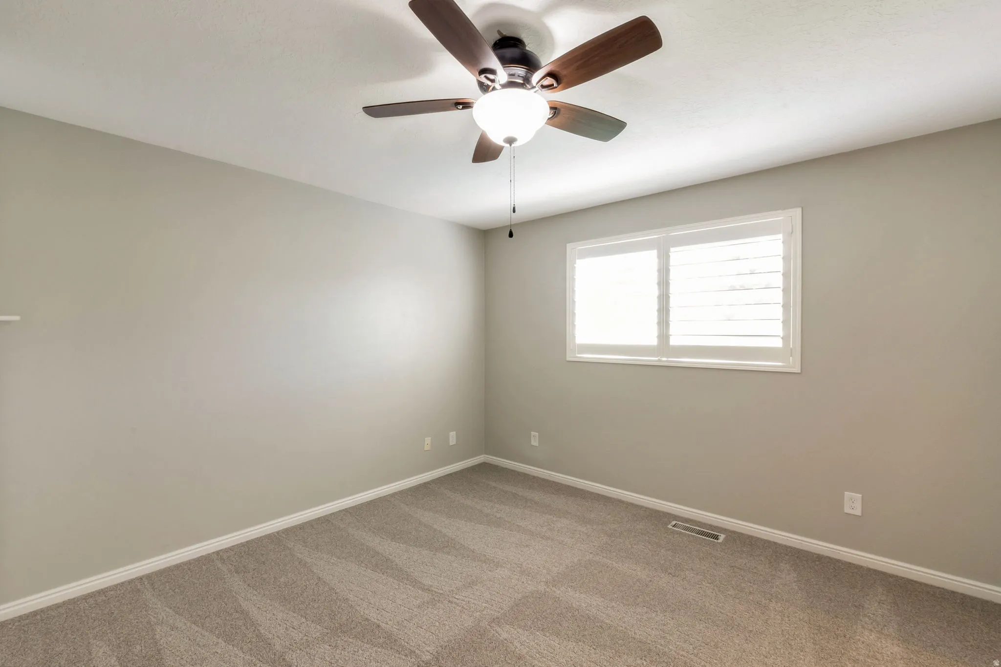 Neutral-toned carpeting and walls complement the white trim and plantation shutters