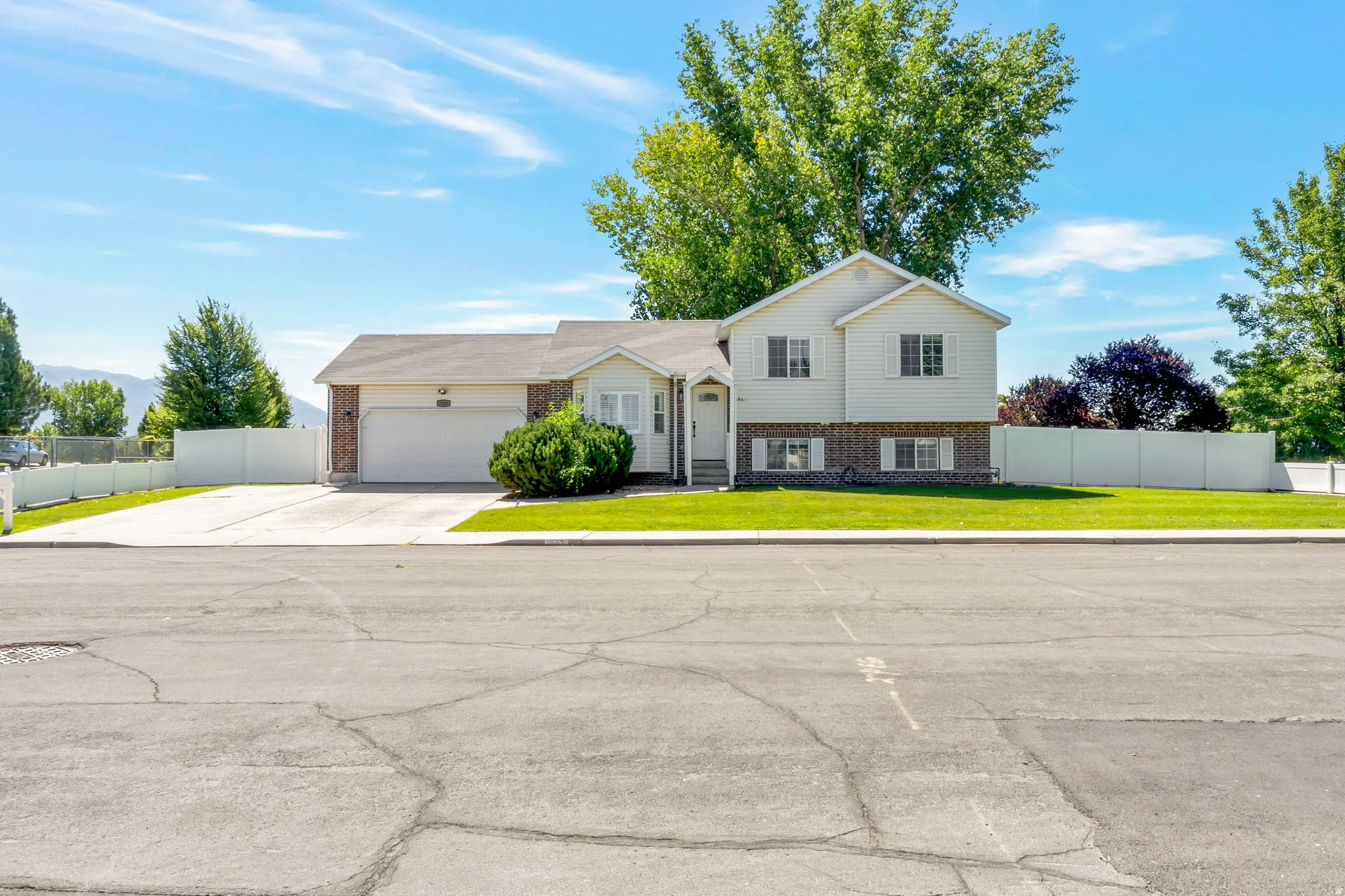 Cream-colored split-level residence with a two-car garage and a paved driveway