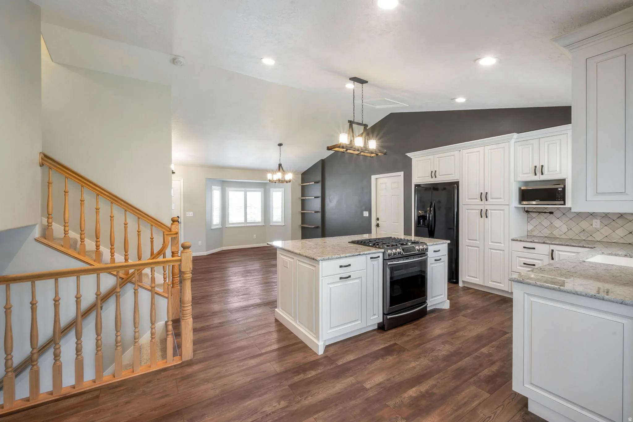 Kitchen featuring wood-finish flooring, white cabinetry, a central island with a built-in range, stone countertops, and a subway tile backsplash